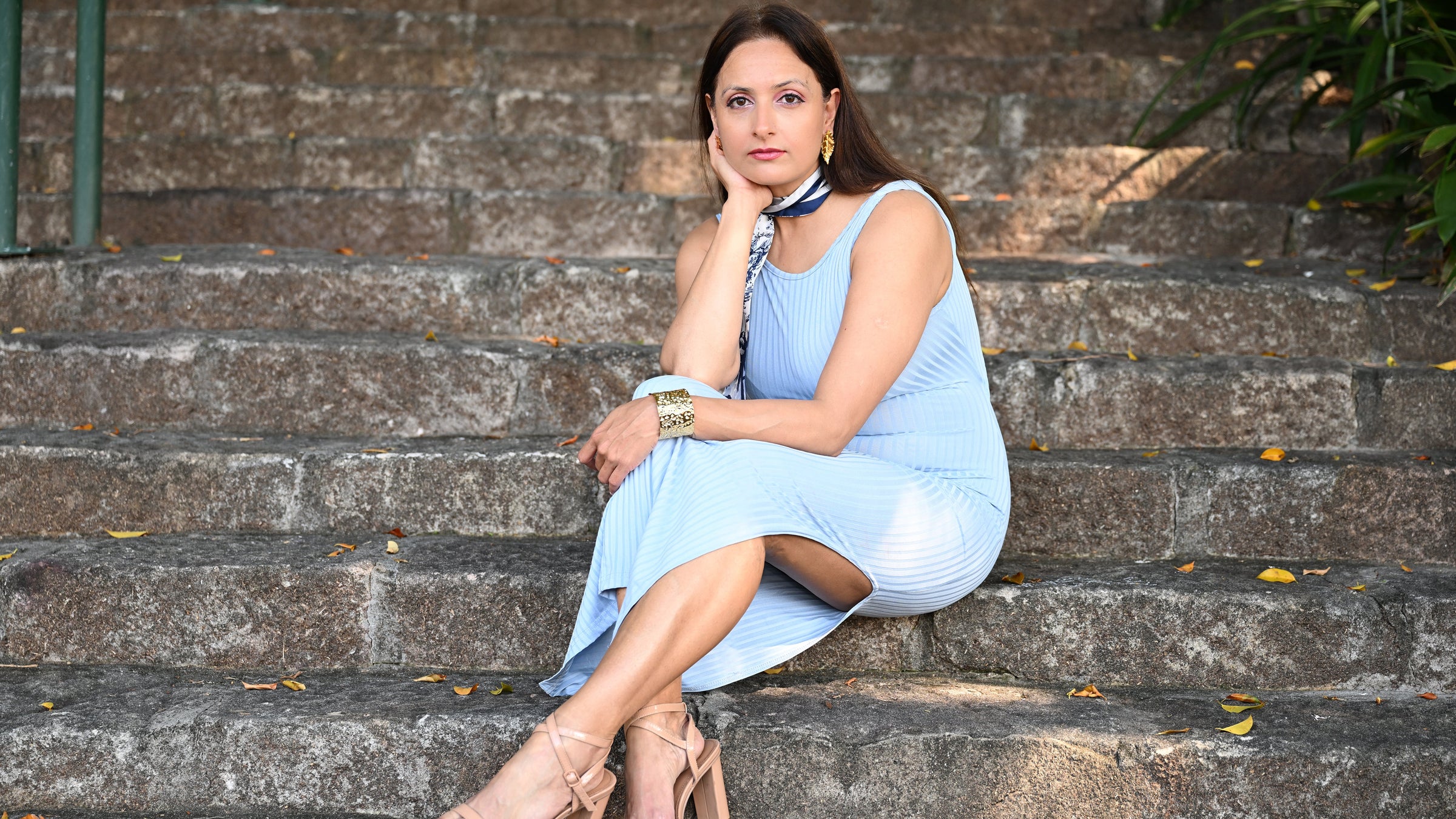 Woman in a light blue dress sitting on stone steps.